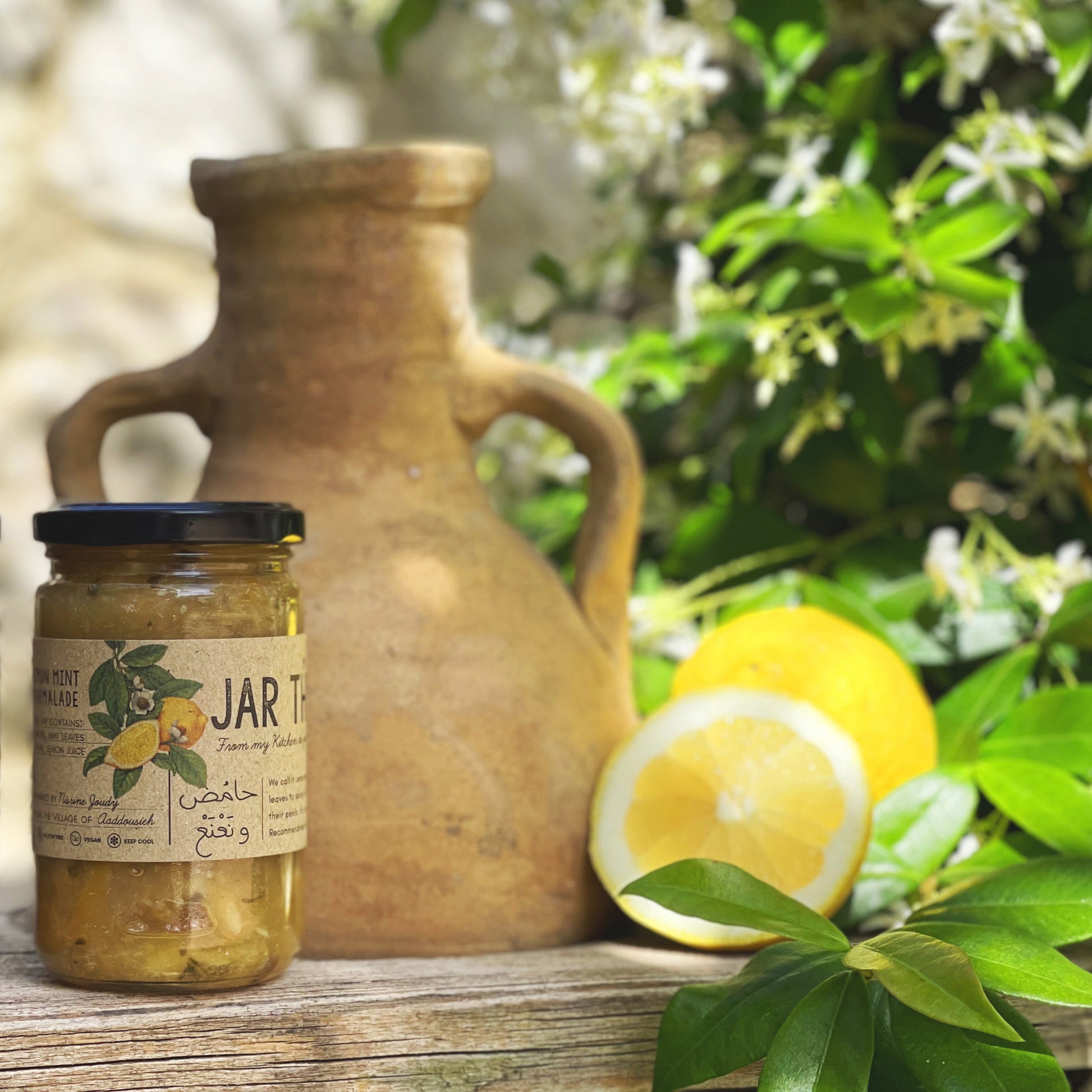 a glass of lemon jam with mint leaves next to a lemon 